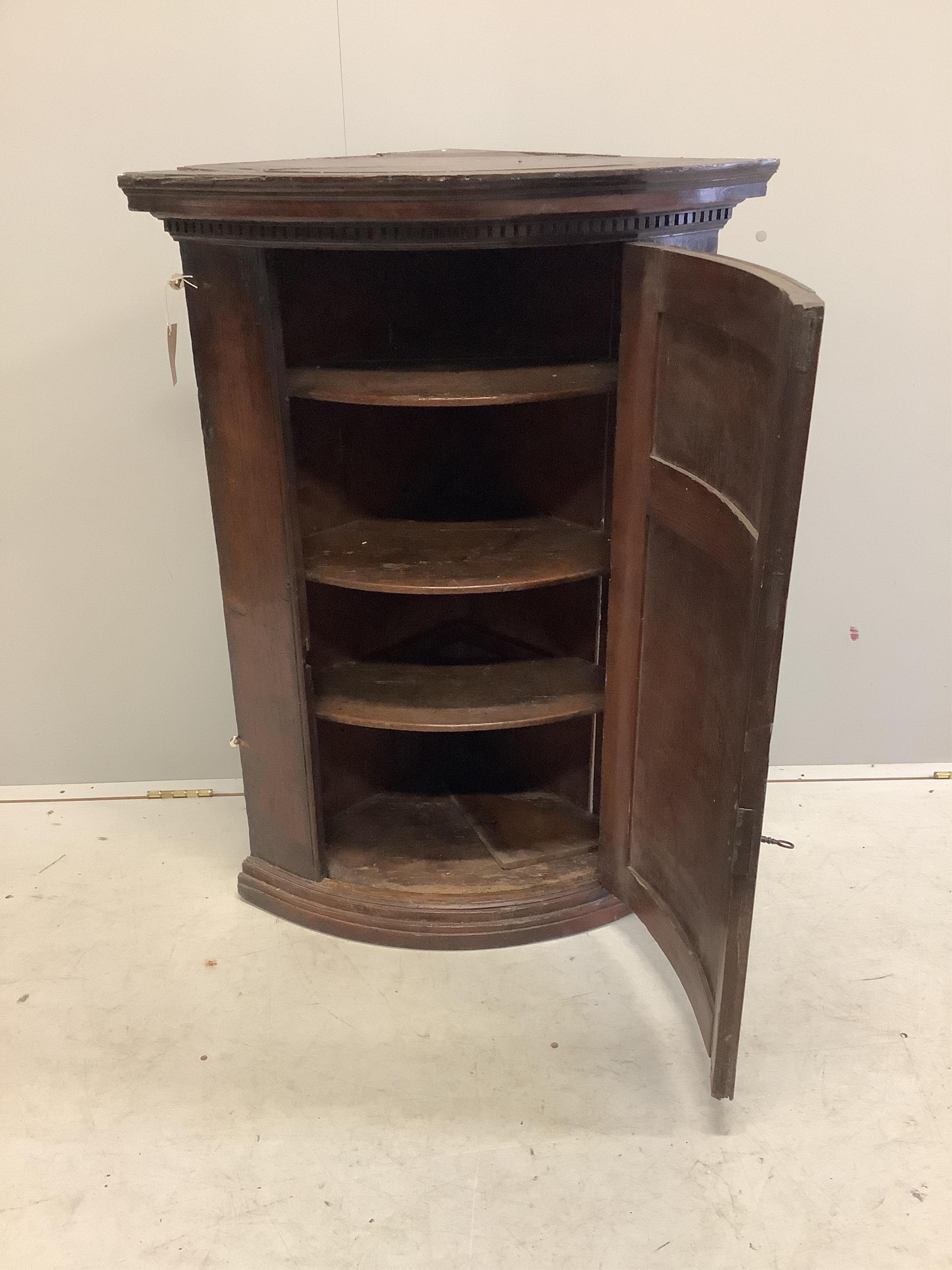 An 18th century pine bow front hanging corner cupboard, width 72cm, depth 46cm, height 101cm. Condition - fair to good